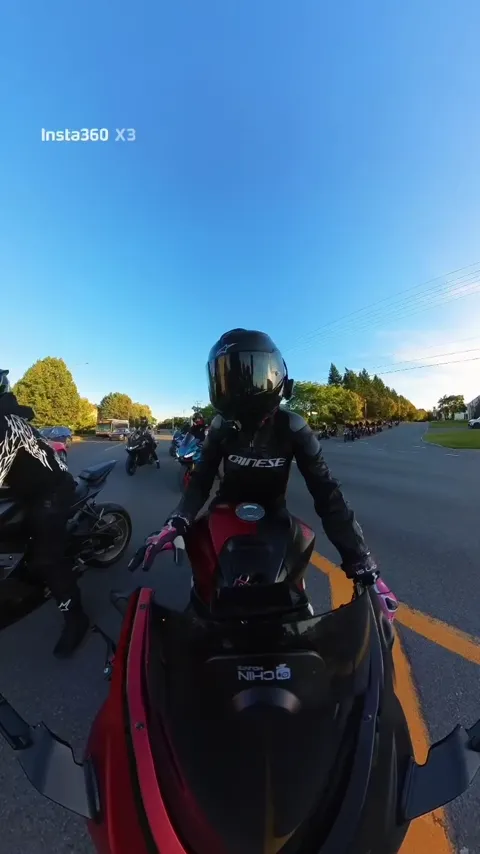 Motocycliste sur une Ninja rouge avec le convoi derrière